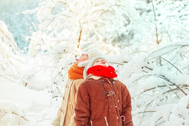 Foto crianças pegam flocos de neve com a boca numa floresta coberta de neve no inverno