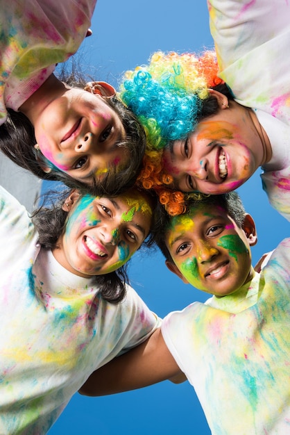 Crianças pequenas, amigos ou irmãos indianos celebrando o festival Holi com gulal ou cor de pó, doces, pichkari ou spray, isolado sobre fundo branco