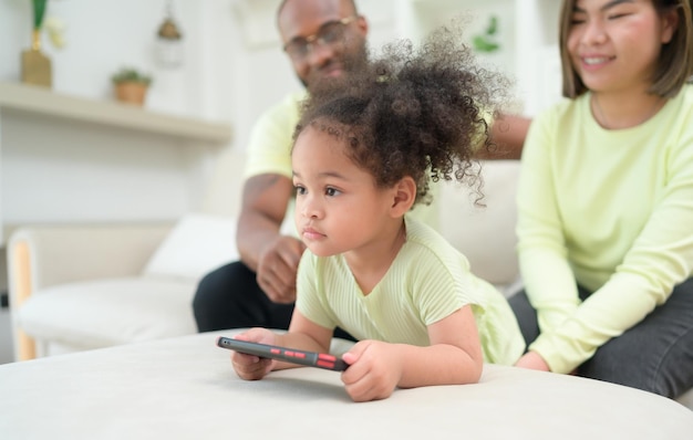 Crianças pequenas brincam e aprendem coisas do mundo inteiro no tablet com os pais para supervisionar e ajudar na sala da casa nas férias