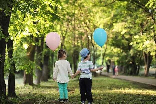 Crianças pequenas estão andando em um parque com balões