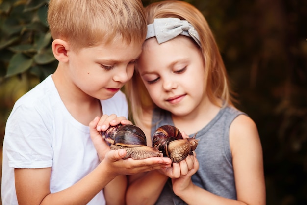 Crianças pequenas, segurando caracóis achatina