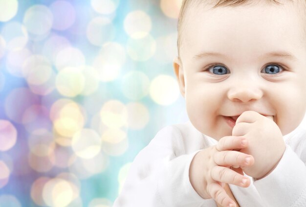 crianças, pessoas, infância e conceito de idade - lindo bebê feliz sobre fundo azul de luzes de férias