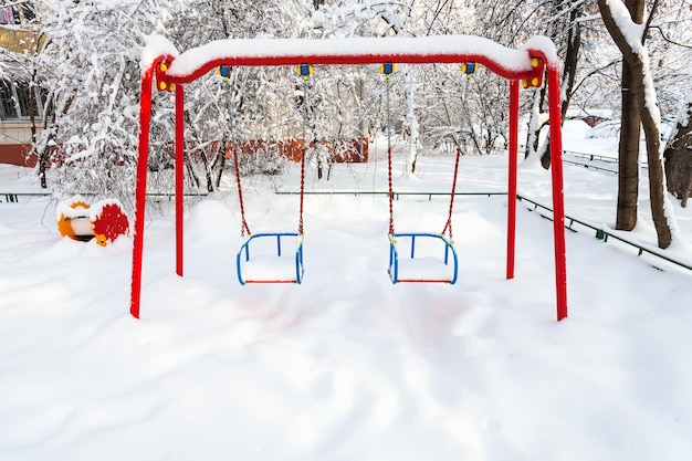 Crianças públicas cobertas de neve balançam no inverno