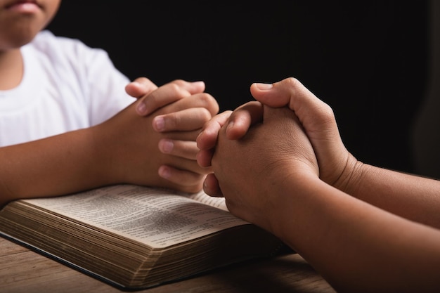 Crianças rezando com a mãe em casa