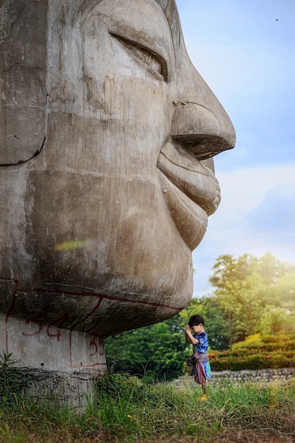 Crianças rezando em frente à estátua de buda