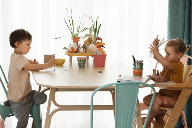 Crianças se divertindo em casa à mesa criando arte feita à mão crianças desenhando e se comunicando em