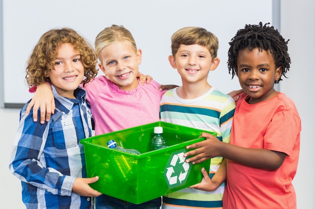 Crianças, segurando a garrafa reciclada na caixa