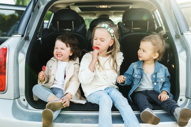 Crianças sentadas no porta-malas de um carro antes de uma viagem