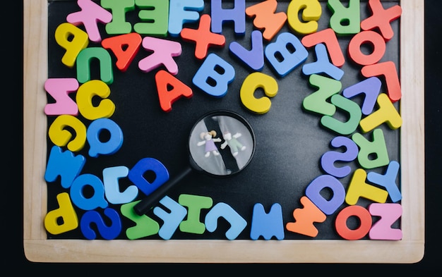 Crianças sob lupa e letras coloridas do alfabeto