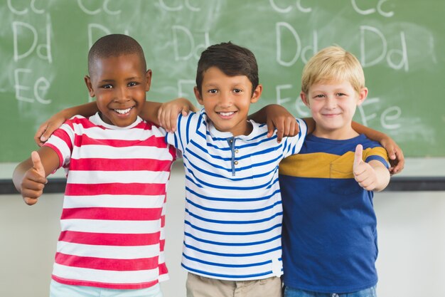 Foto crianças sorridentes, mostrando os polegares em sala de aula