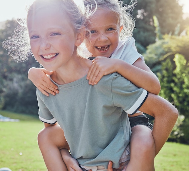 Crianças sorriem e irmã pegando carona menina ao ar livre sendo brincalhona feliz ou relaxam juntas nas férias de verão Irmãs irmãs e brincando animadas na grama crianças se divertem e aproveitam o encontro ou o jogo