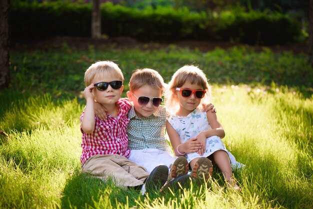 Crianças sorrindo no jardim em óculos de sol