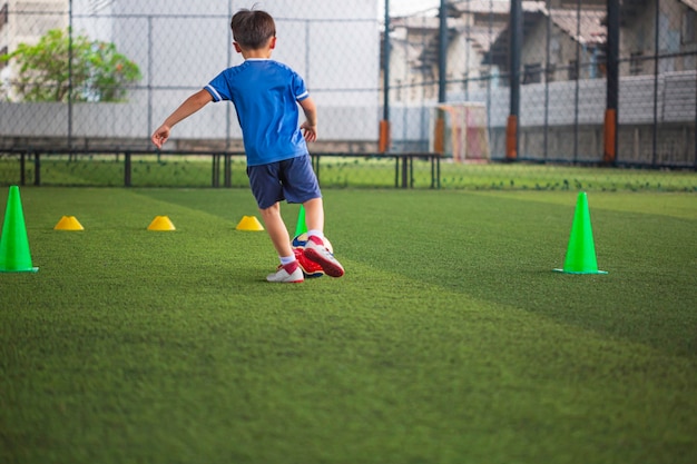 Crianças táticas de bola de futebol controlam a bola em um campo de grama com cone para treinamento