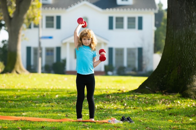 Crianças tendo atividades esportivas de treino crianças ao ar livre levantando um haltere