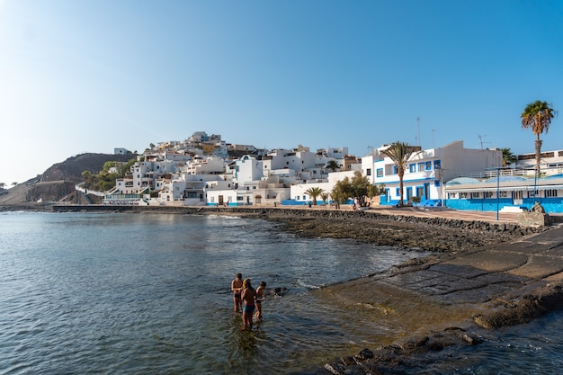 Crianças tomando banho na praia da cidade costeira de Las Playitas, costa leste da ilha de Fuerteventura, nas Ilhas Canárias. Espanha