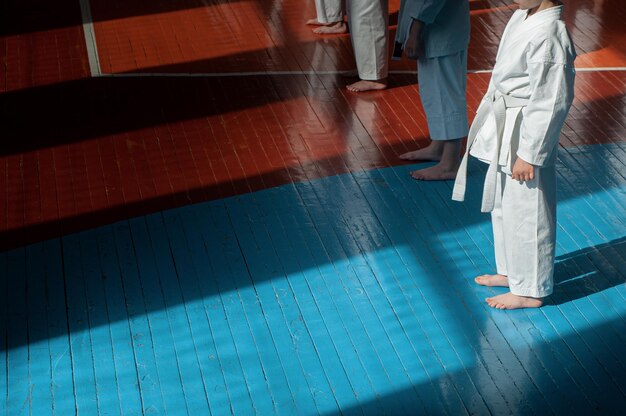 Crianças treinando karatedo Jovens atletas em quimonos tradicionalmente brancos com cintos coloridos Banner com espaço para texto Para páginas da web ou impressão de publicidade Foto sem rostos