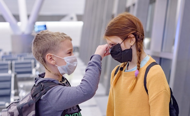 Crianças um menino e uma menina no aeroporto em uma máscara protetora