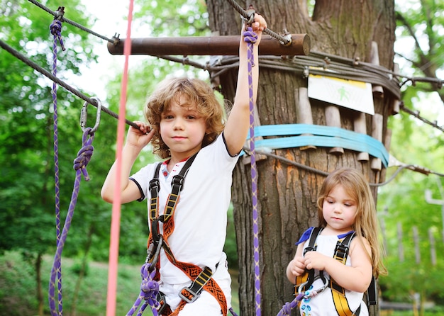 Crianças - um menino e uma menina no parque de corda passar obstáculos