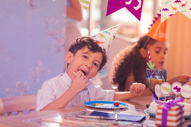 Crianças usando chapéus de festa e curtindo a comida