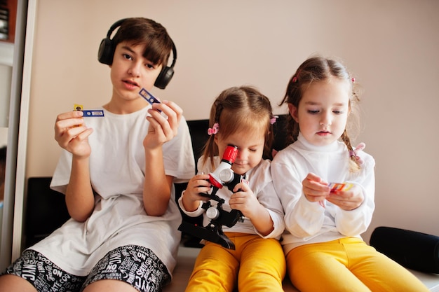 Crianças usando microscópio aprendendo aula de ciências em casa.