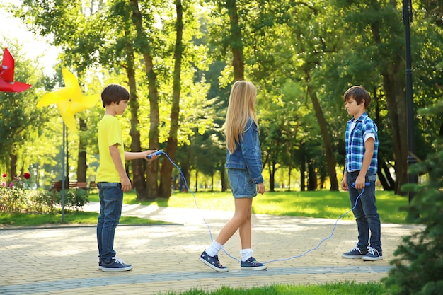 Criancinhas fofas pulando corda no parque