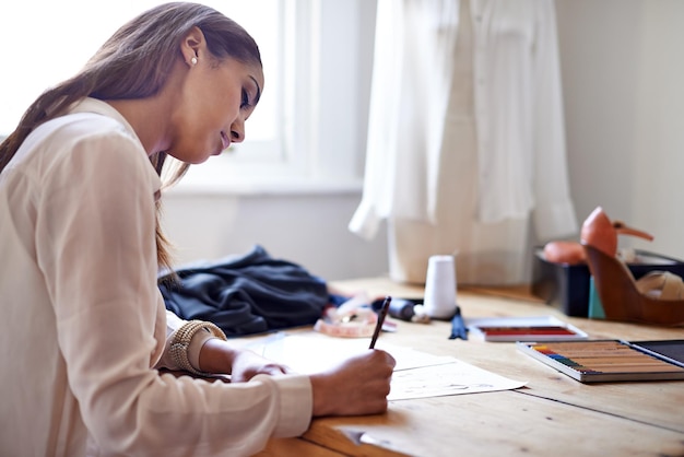 Foto criando novas tendências de estilo uma estilista desenhando esboços em seu escritório