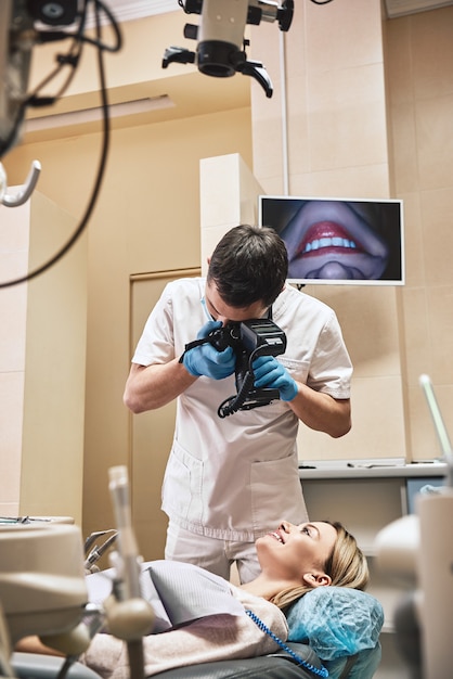 Criando sorrisos mais brilhantes no dentista com a câmera, fazendo fotos de pacientes sorrindo após o tratamento especial