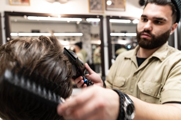 Criando um novo penteado. Corte de cabelo criativo de cabeleireiro. Salão de beleza masculino