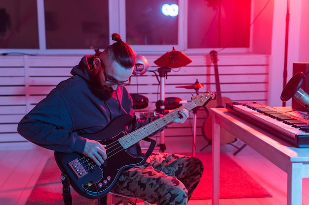 Criar música e um conceito de estúdio de gravação - Guitarrista de homem engraçado barbudo gravando baixo elétrico