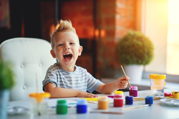 Criatividade infantil feliz garoto engraçado desenha tintas no jardim de infância