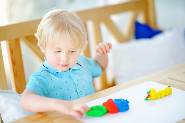 Criativo menino brincando com argila de modelagem colorida no jardim de infância