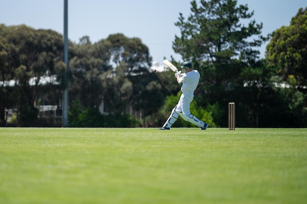 Cricketspieler schlägt auf einem Cricketfeld ein lokales Cricketspiel, das im Sommer in Australien auf einem grünen Cricket-Oval ausgetragen wird