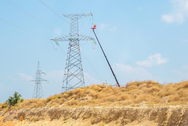 Crimea, Rusia - 08.20.2019: los electricistas elevados a una altura se dedican al mantenimiento de una línea eléctrica