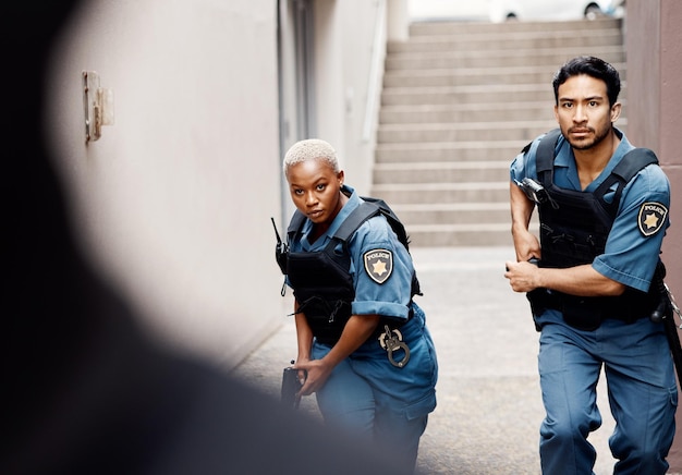 Crimen policial y equipo en la ciudad para la protección de la justicia y la misión de aplicación de la ley Colaboración seria y jóvenes agentes de seguridad trabajando juntos con armas en una ciudad urbana