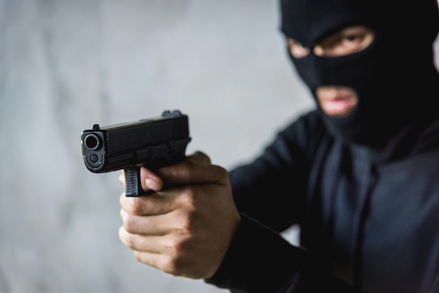 Criminoso masculino atacando com arma de mão apontando arma para o alvo na frente, conceito de ladrão