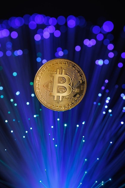 La criptomoneda Bitcoin brillante contra el fondo de los cables de fibra óptica para la minería de criptomonedas