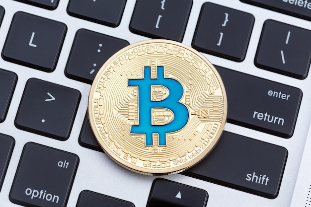 Criptomoneda bitcoin dorada en el teclado de la computadora