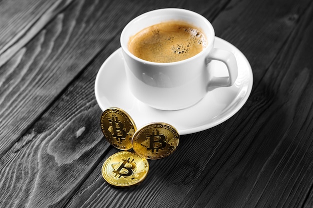 Criptomoneda dorada bitcoin de pie en la taza de café