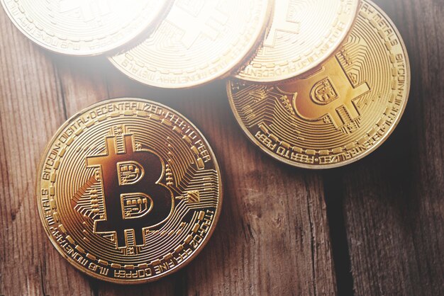 Criptomoneda de símbolo físico. Bitcoins dorados sobre un fondo de madera