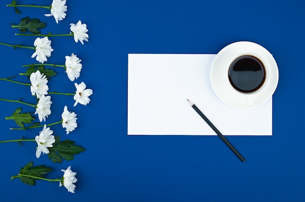 Crisantemos blancos con nota de tarjeta de papel sobre fondo azul. Para hacer la lista de consept. Patrón floral