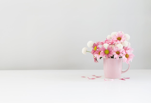 crisântemos brancos e cor-de-rosa em copo rosa em fundo branco