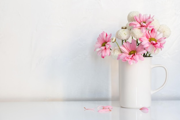 Crisântemos brancos e rosa em copo vintage em fundo branco