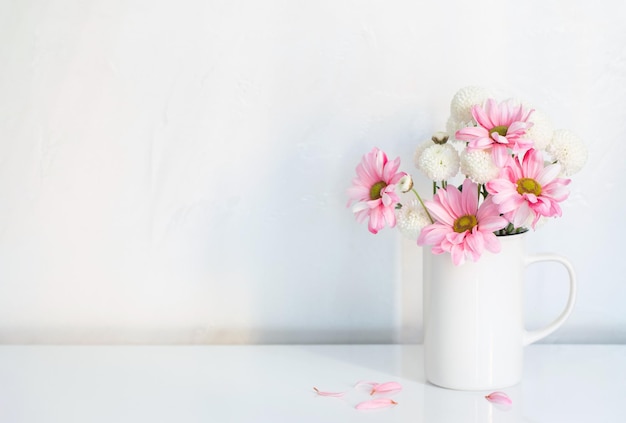 Crisântemos brancos e rosa em copo vintage em fundo branco