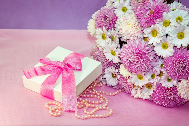 Crisantemos y ramo de aster y caja de regalo con cinta rosa