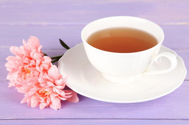 Crisantemos rosas y taza de té en la mesa de madera