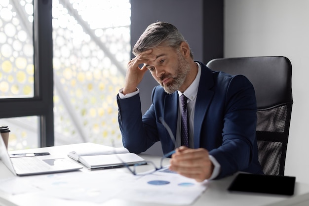 Crise de empreendedorismo deprimido empresário de meia-idade sentado no local de trabalho no escritório