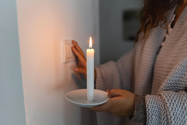 Crise de energia Mão na escuridão completa segurando uma vela tentando acender a luz durante uma queda de energia Conceito de blackout