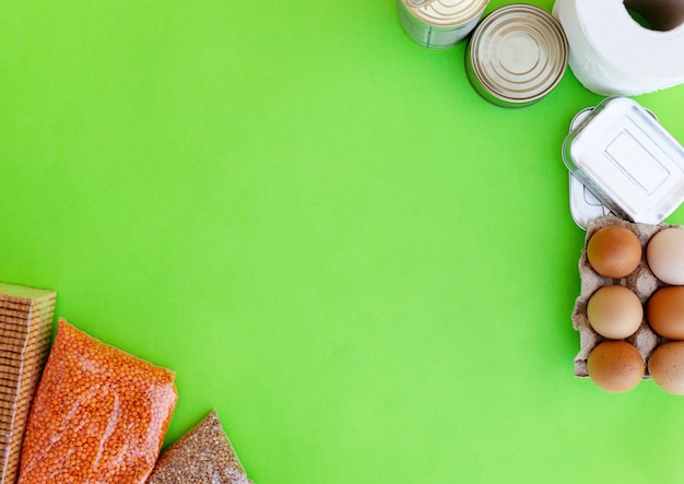 Crise de suprimentos de alimentos estoque de alimentos para o período de isolamento de quarentena em fundo verde. Trigo mourisco. lentilhas, comida enlatada, papel higiênico. Entrega de comida, doação, quarentena de coronavírus. Copyspace.