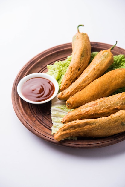 Crispy Green Chilli Pakora o Mirchi Bajji, servido con salsa de tomate sobre un fondo de mal humor. Es un bocadillo popular para la hora del té en la India, especialmente en Monzón. Enfoque selectivo