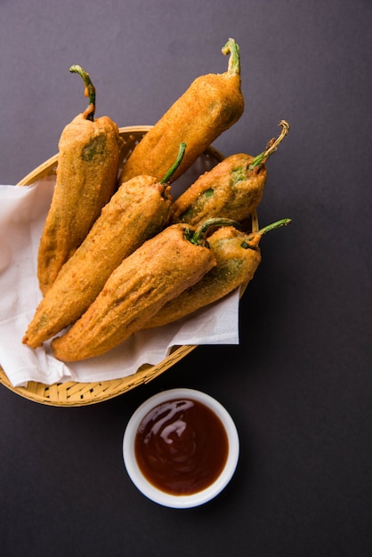 Crispy Green Chilli Pakora o Mirchi Bajji, servido con salsa de tomate sobre un fondo de mal humor. Es un bocadillo popular para la hora del té en la India, especialmente en Monzón. Enfoque selectivo